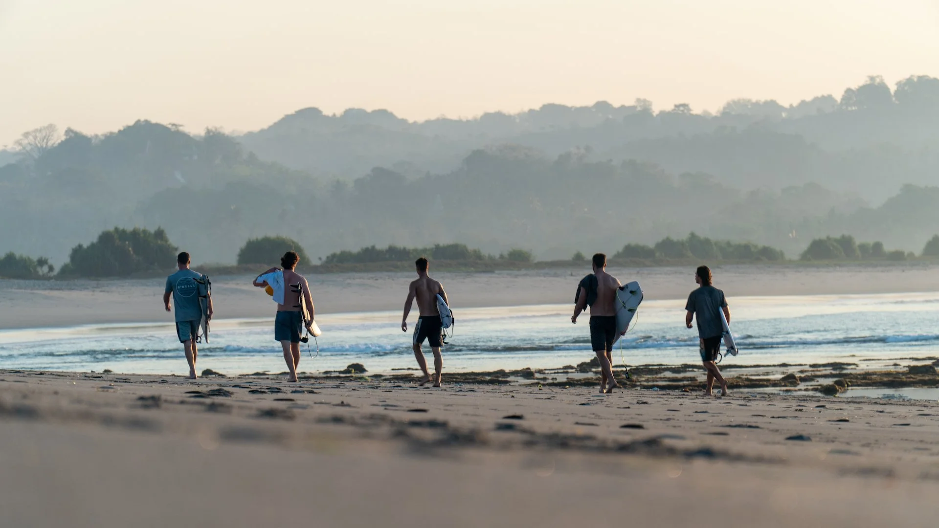 Surfers walking the beach at dawn